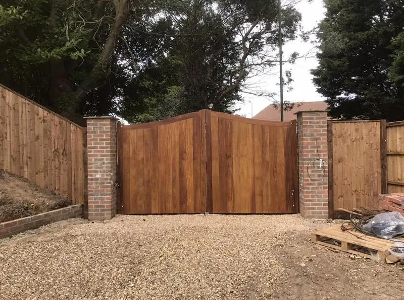 Curved-top timber driveway gates between brick piers
